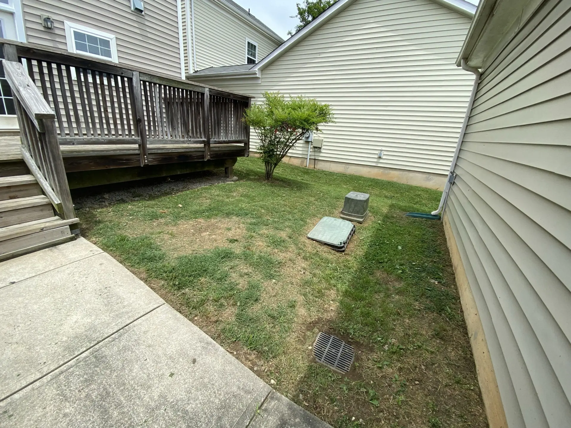Narrow side yard trimmed neatly around utility boxes and deck