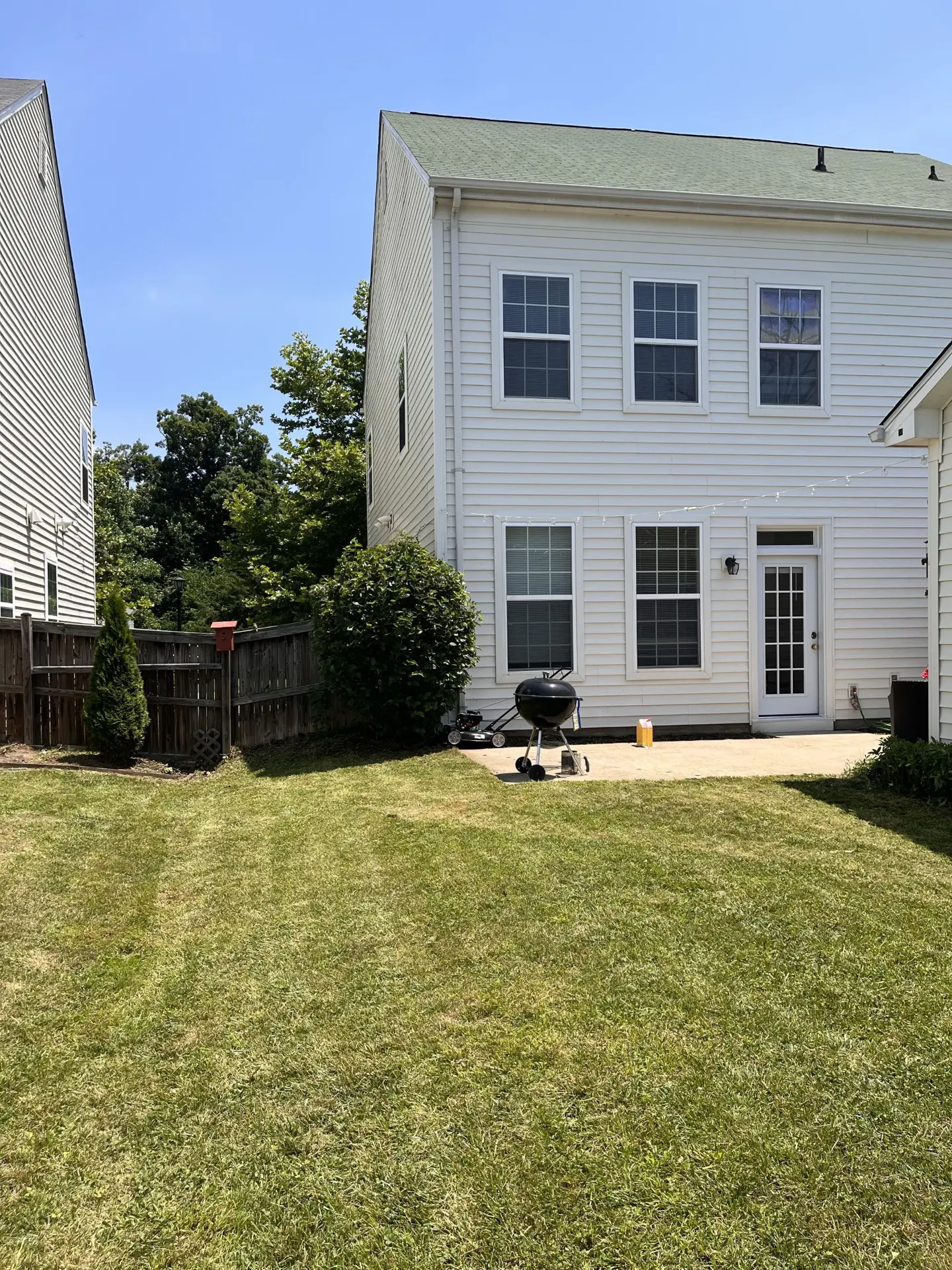 Backyard lawn with clean mowing stripes behind a two-story home